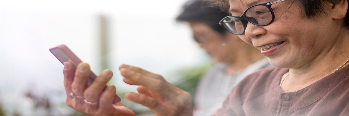Photo of an older woman with glasses looking at a smartphone