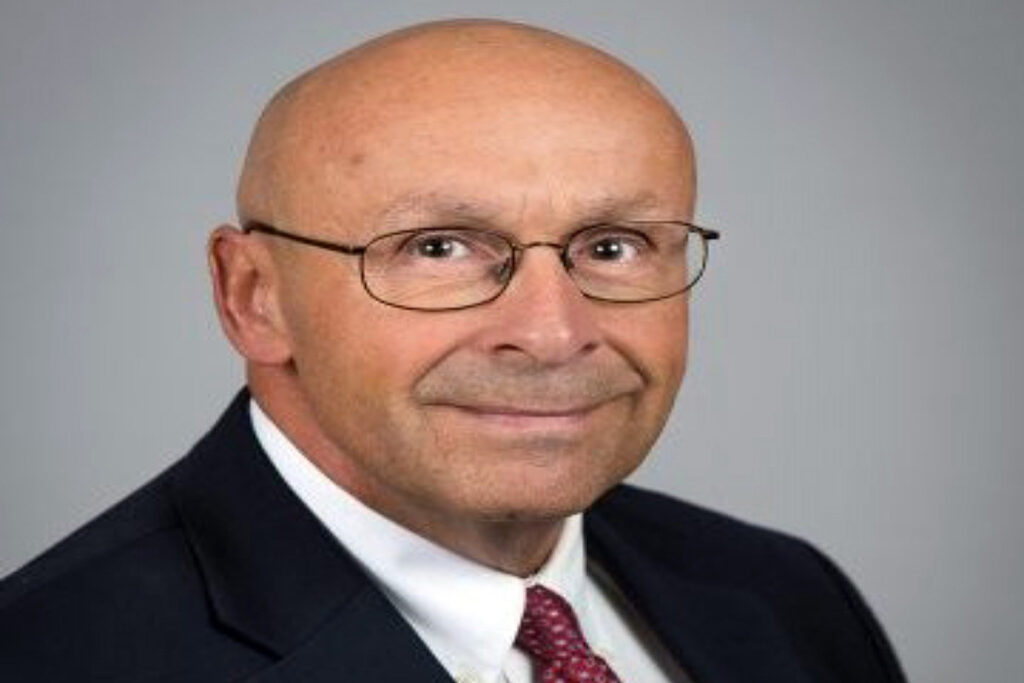 Headshot photo of Linwood Gehris, who is wearing a black suit jacket and a red tie