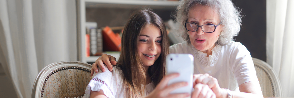 Photo of an older woman and a young girl looking at smartphone