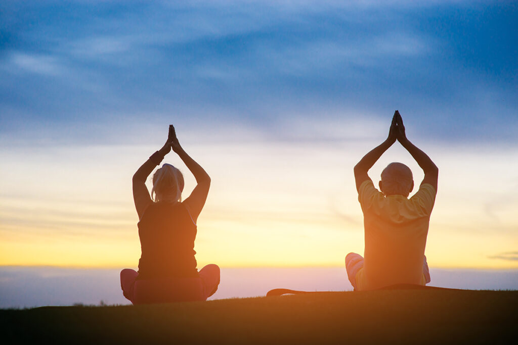 Photo of two people meditating on the ground outdoors