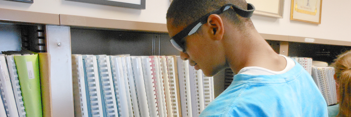 Photo of a young man browsing books in the Posch Braille Library