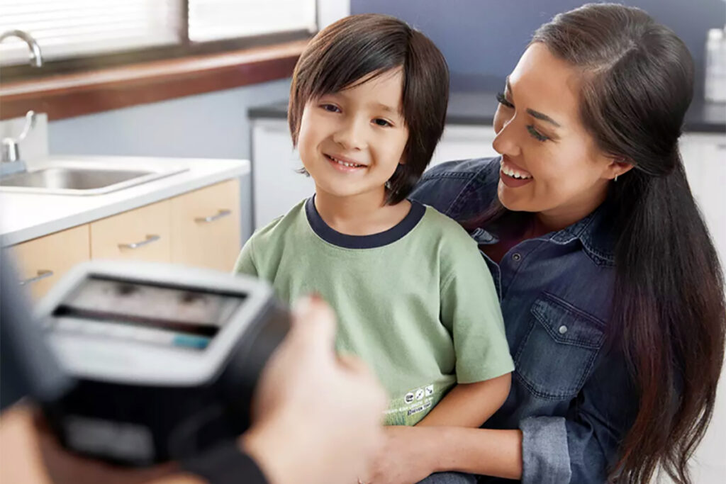 Photo of a young boy being screened for visual impairments by a Spot Vision Screener