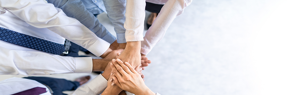 Photo of several stacked hands to signify unity and collaboration