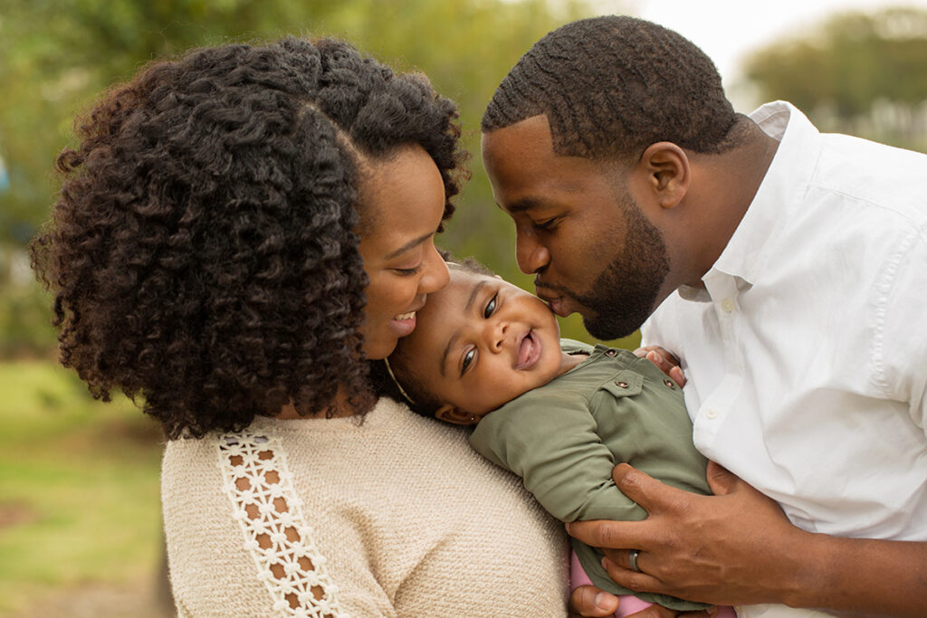 Photo of a mother and father holding a baby girl.