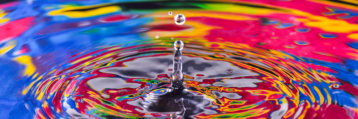 A water drop splashing into water reflecting vibrant colors