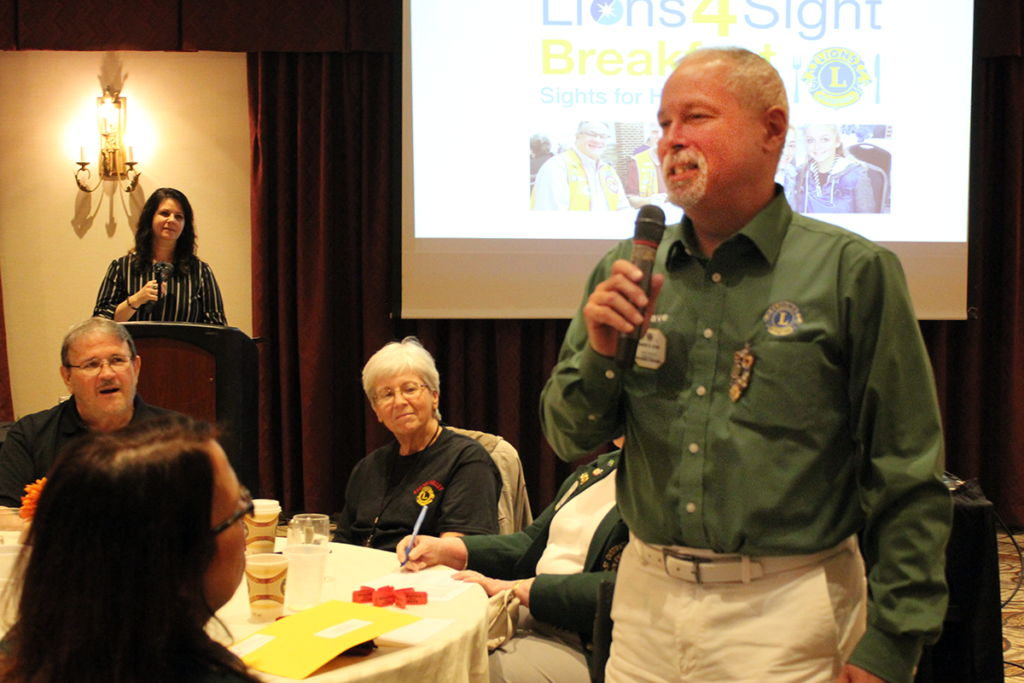 Lion David Leon speaking to a crowd with a hand-held microphone