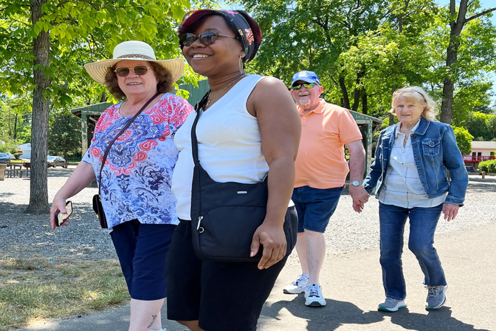 Three Sights for Hope clients and one volunteer walking in a park with smiles on their faces